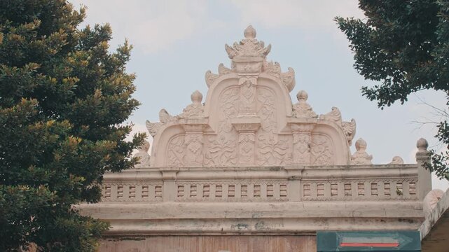 Architectural detail of an ornate stone gate in Yogyakarta featuring intricate traditional carvings and historical motifs against a clear sky, captured with a cinematic aesthetic.