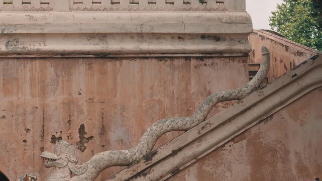 Ornate stone carving of a mythical Naga serpent adorning the staircase of an old weathered temple, reflecting Southeast Asian religious architecture and historical preservation.