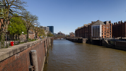 Fototapeta premium View along Hamburg canal with brick warehouses and bridge in Speicherstadt district