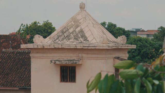 A close-up view of an intricately designed traditional roof spire on a historic building in Indonesia, showcasing detailed stonework, weathered textures, and cultural heritage.