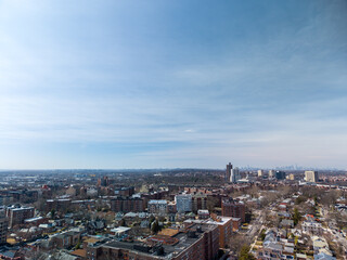 Obraz premium Expansive urban landscape view encompassing residential neighborhoods. Commercial zones. And the iconic new york city skyline in the distance under a clear blue sky