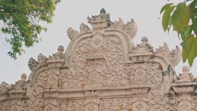 A detailed close-up of an intricate Javanese architectural stone relief featuring ornate floral motifs and cultural patterns at a historic Indonesian palace site.