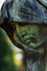 Fototapeta premium Sad angel statue resting head on hand, symbolizing deep sorrow, contemplation, and emotional vulnerability in a quiet and intimate composition.