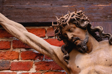 Fototapeta premium Jesus Christ on the cross against brick wall, symbolizing sacrifice, suffering and faith in Christian spirituality and religious devotion.