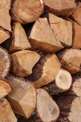 Fototapeta premium Stacked wooden logs. Close-up of stacked firewood. Natural wooden background. Background of chopped firewood ready to use. Suitable for themes related to heating, nature or rural life