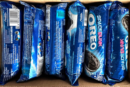 stack blue oreo cookie packages in cardboard box, supermarket goods, global food distribution scattered candy, close-up sweet snacks, Sustainable consumerism, textured background commercial branding