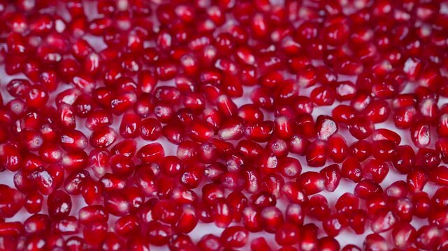 Studio illumination accentuates shiny pomegranate seeds and detailed textures. Expert lighting showcases glossy surface and intricate structure of pomegranate arils in high detail