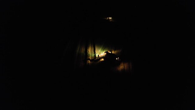 Combine harvesters working on grain field at night with bright lights captured as aerial panorama documenting intensive agricultural harvest with modern machinery