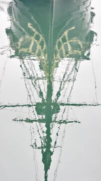 Vertical pan from the water reflection of Etoile du Roy&rsquo;s masts up to the ship and full rigging in Saint Malo, Brittany, France, highlighting structure and maritime detail in portrait format