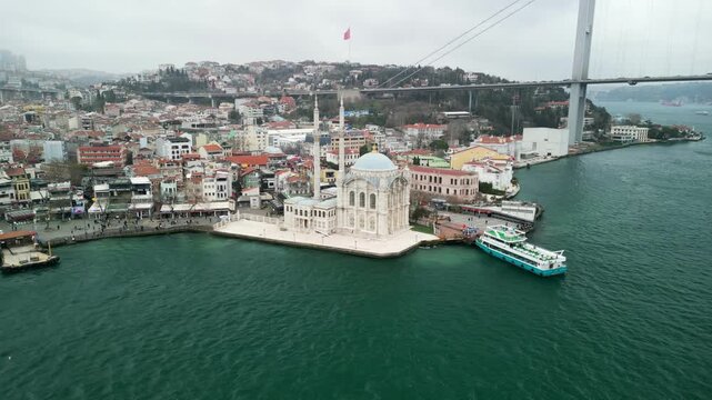 Grand Mecidiye Ortakoy Mosque with martyrs bridge in the back flying back shot
