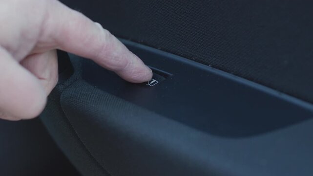 Person pressing car power window switch button
