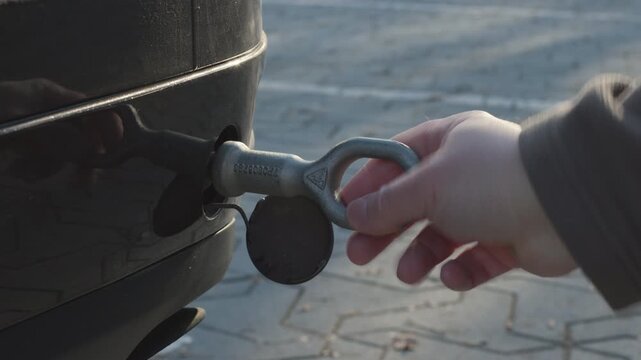 Mechanic installing a towing eye hook on a black car