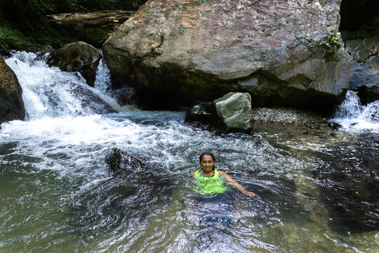 Women relaxing in a natural river stream in the lush South American tropical forest