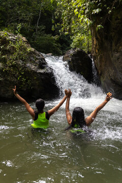 Group of women bathing in a fresh river surrounded by lush tropical rainforest in the Venezuelan Caribbean. waterfall in the forest