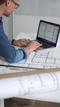 Architect drawing and measuring blueprints on a desk, creating detailed floor plans and designs for construction projects, demonstrating precision and expertise in architectural planning