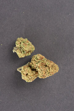 Three cannabis buds with green and orange hues are displayed on a dark background.