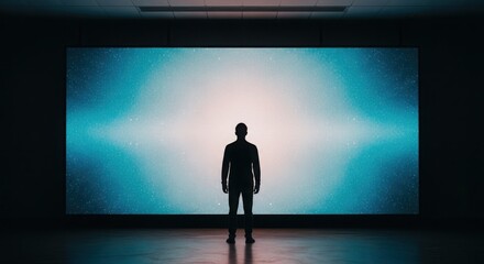 Fototapeta premium A solitary silhouette of a man stands before a vast, luminous abstract display in a modern art gallery.