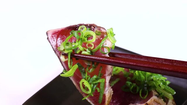 カツオのたたきを箸で持ち上げる　食べる様子