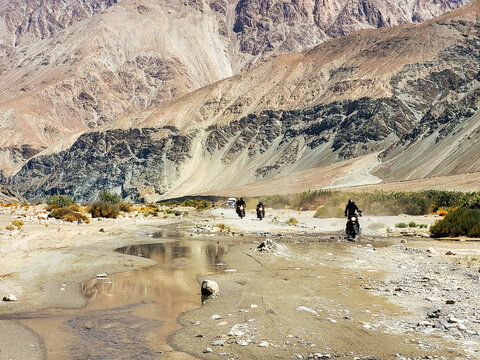 Adventure Motorcyclists Crossing a Shallow River Stream on a Rugged Mountain Path in Agam toward Wari La, Ladakh