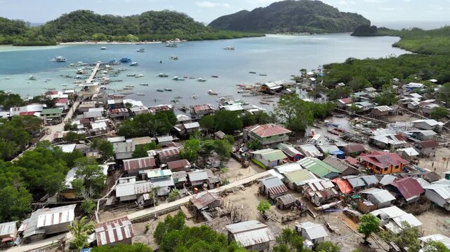 Horizontal panning riser drone shot above informal coastal houses built along mangrove areas in Linapacan, Palawan, Philippines