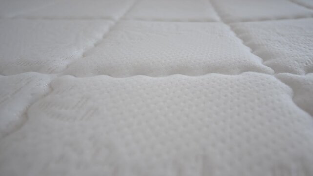 White quilted mattress surface with intricate floral patterns and soft texture close up.