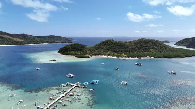 POI drone shot of a small fish port in Linapacan with docked boats and clear turquoise waters during a bright morning, Philippines