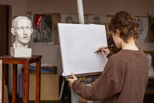 An artist draws a man's head from a plaster cast. Actual photo of an art studio. 