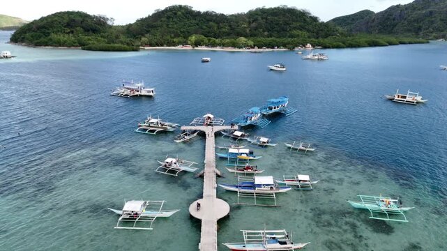 Flyover drone shot of the fishing port in Linapacan with docked boats and scenic island backdrop, Philippines