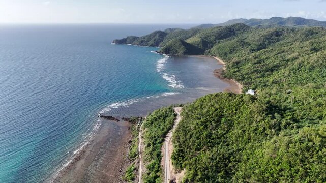 Flyover drone shot of Linapacan Island coastline with turquoise waters and gentle waves rolling over the reef, Philippines