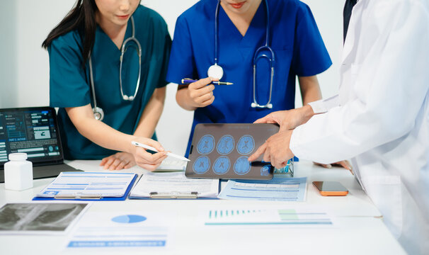 Doctors and nurses reviewing brain scan on tablet for diagnosis, teamwork and data analysis in modern hospital, professional healthcare service