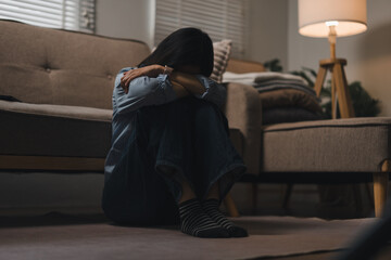 Lonely depressed woman sitting on the floor in a dimly lit living room at home © PRIME STOCK LAB