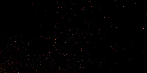 Blur, bokeh, fire, red light, tiny specks created by the heat energy of burning fuel on a black background. © Arteekom