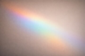 Fototapeta premium A vibrant diagonal rainbow spectrum of light cast onto a plain, light-colored wall, showcasing the full range of colors from red to violet.