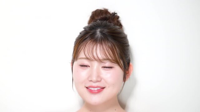 お団子のアップヘアのかわいい女性の美容とスキンケアの悩みイメージの動画　カメラ目線の笑顔