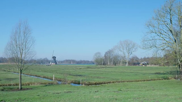 Dutch windmill turning sails in a polder landscape