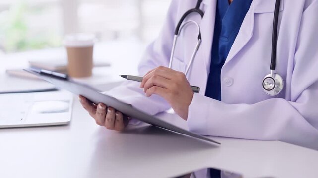 Asian adult medical professional documenting patient records writing essential notes during consultation in clinic office healthcare examination