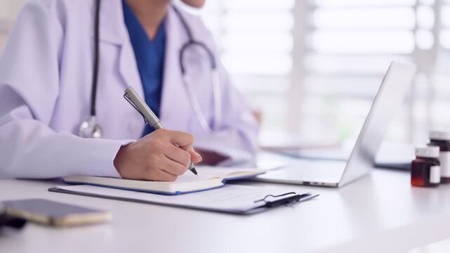 Medical professional doctor hand writing notes patient chart medical report documents clinic office laptop healthcare research physician record keeping prescription