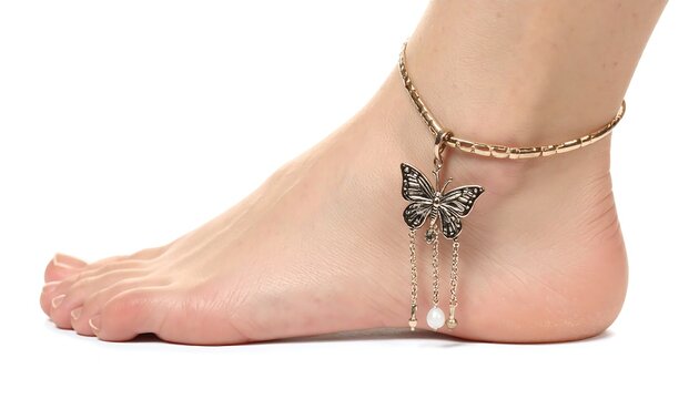 Fair-skinned foot with a butterfly anklet featuring dangling chains and a pearl, against a clean white backdrop