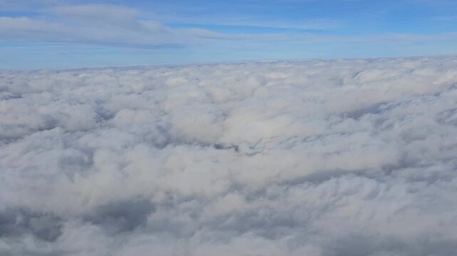 Beautiful aerial video flying over a dense, endless sea of textured white stratocumulus clouds high above the Andaman and Nicobar Islands.
