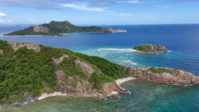 Portrait orientation pull-away panning drone shot over Ile Island showcasing limestone formations, turquoise waters below, and Linapacan town in the distance, Philippines