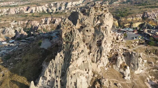Drone aerial video of Uchisar Castle in Cappadocia, Turkey with the drone flying backward while the camera tilts upward revealing the iconic rock fortress and surrounding landscape.