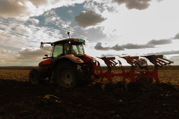 Tractor plowing field the land at sunset