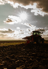Tractor plowing field the land at sunset