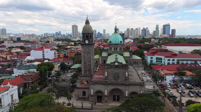 Aerial drone view of Manila Cathedral in Intramuros with modern skyline in the background. Historic architecture meets urban cityscape in Manila, Philippines.