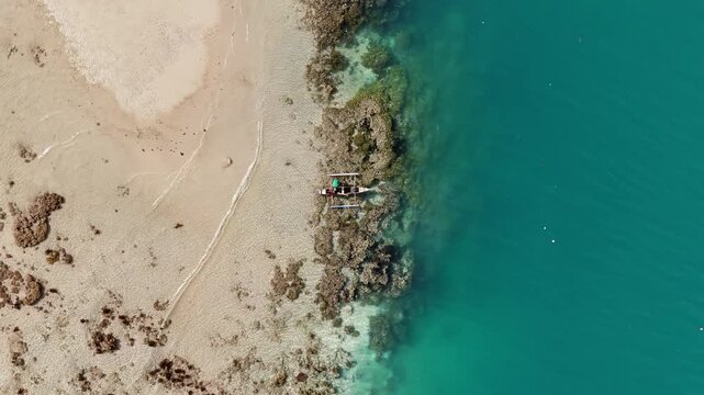 POI riser helix drone shot of a fisherman on a small outrigger boat fishing in a reef at Linapacan, Palawan, Philippines