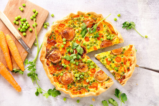 Vegetable quiche with goat cheese, carrots and green peas, top view