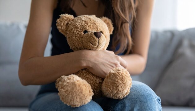 すわりながらクマのぬいぐるみを抱える女性の写真