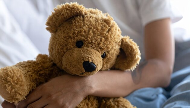 すわりながらクマのぬいぐるみを抱える女性の写真