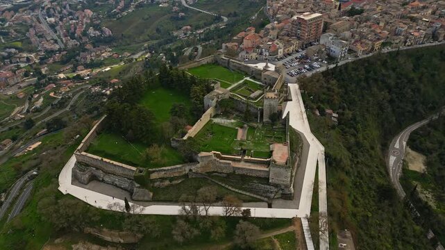Aerial view of Lombard castle in Enna, showcasing the expansive green grounds, stone walls, and surrounding cityscape, highlighting historical architecture and natural beauty
