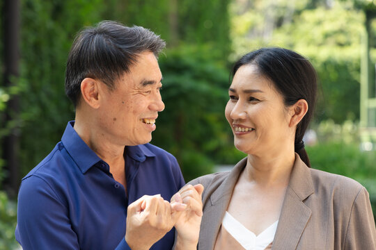 Asian Senior man hooking little finger for pinky promise with middle aged old wife, concept image for family reunion, middle-aged couple togetherness, lovely family promise